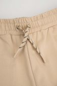 Дитячі бавовняні штани Coccodrillo колір бежевий однотонні (3477834)